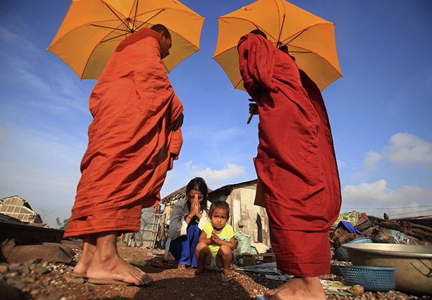 Buddhist monks and the praying woman in Cambodia